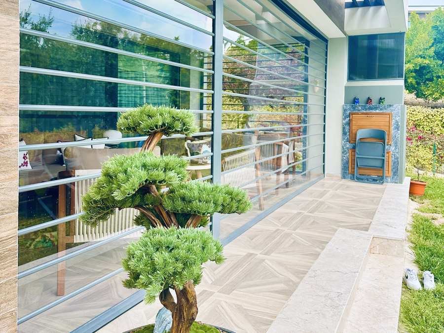 Bonsai ağaçlı terasta şeffaf panjur uygulaması
