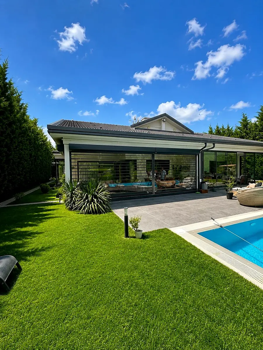 Terraza de villa cerrada con persianas transparentes Solidroll junto a una piscina